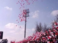 Foto: "gran cantidad de globos blancos y rojos recibiendo al equipo" Barra: Los Marginales • Club: Curicó Unido
